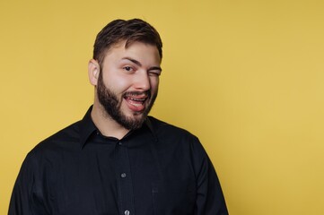 Obraz premium Man winks and smiles against a plain yellow background in a casual setting