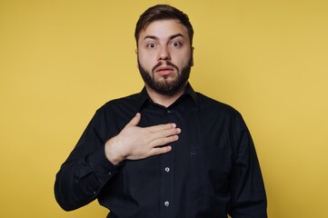 Surprised man with beard shows shock at unexpected news in indoor setting with yellow background