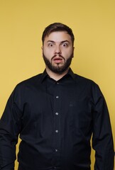 Obraz premium Man shows surprise expression in front of bright yellow background during indoor setting