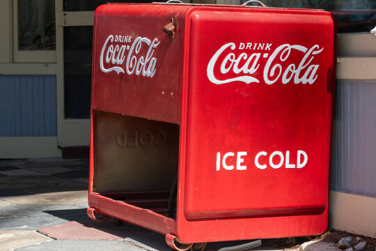 Orlando, Florida, US-December 1, 2025: A bright red metal vintage Coca-Cola cooler. The 1920s double lid galvanized interior cooler features a storage rack on the lower section and raised casters. 