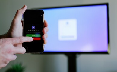 Middle Aged Man Working From Home Remotely is Prompted for Multi Factor Authentication Approval While Signing In Work Computer Cybersecurity Concept