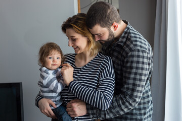 Young parents being affectionate while holding their 7-month-old infant son at home