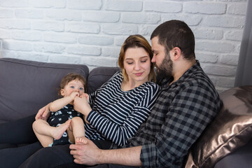 Young parents being affectionate while holding their 7-month-old infant son at home