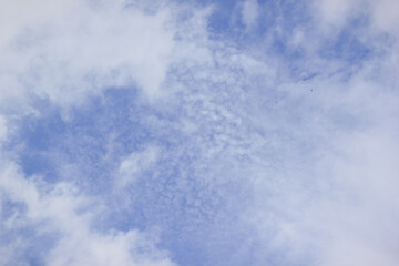 Bright blue sky with white, patchy clouds on a sunny day providing a peaceful background