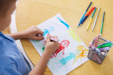Cute little boy drawing family at wooden table indoors, closeup