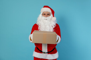Santa Claus with parcel on light blue background