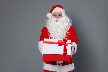 Santa Claus with Christmas gift on grey background
