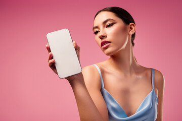 Gorgeous elegant woman posing with smartphone against pink background, emphasizing modern beauty and style