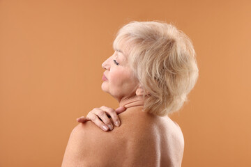 Beautiful senior woman on pale orange background, back view