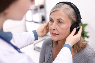 Hearing test. Doctor adjusting patient's audiometric headphones in clinic, closeup