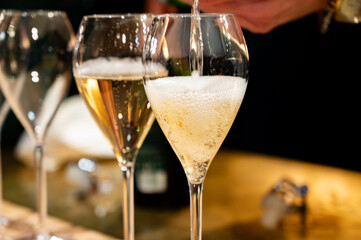 Pouring in glasses of french sparkling wine champagne with little bubbles, tasting wine, celebration, wedding or champagne tour with visit of caves, Reims, France