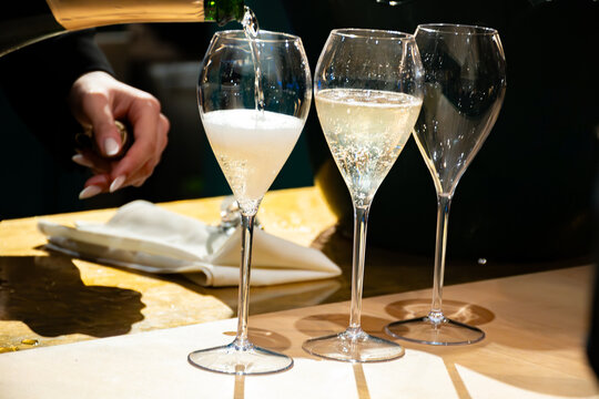 Pouring in glasses of french sparkling wine champagne with little bubbles, tasting wine, celebration, wedding or champagne tour with visit of caves, Reims, France