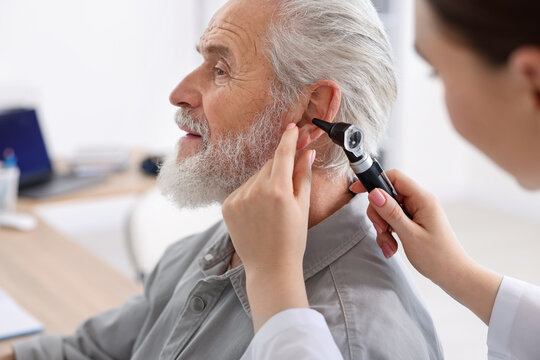 Hearing test. Doctor examining patient&rsquo;s ear with otoscope in clinic