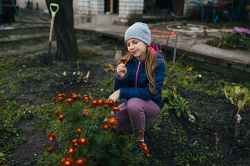 Photograph, portrait of a child, teenage girl in a garden, vegetable garden with plants, with many flowers, marigolds, autumn, outdoors.