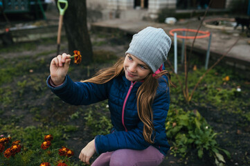 Photograph, portrait of a child, teenage girl in a garden, vegetable garden with plants, flowers, marigolds, autumn, outdoors.