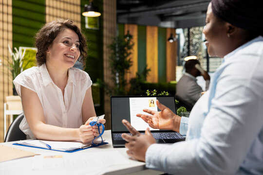 Smiling female applicant receiving access security card from the HR manager during an onboarding interview, confirming employment approval and registration into the new workplace.