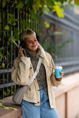 Fototapeta premium Woman enjoying music and coffee on autumn street