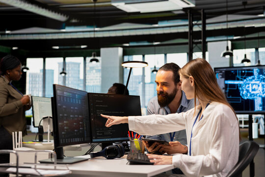 Friendly team leader mentor explaining young software engineer how to use AI tech. Joyous supervisor guiding office newcomer through AI tool integration, mentoring her on using neural networks APIs