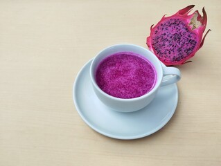 Dragon fruit juice in white cup with fresh fruit on wooden table background. Healthy drink lifestyle. High angle view	