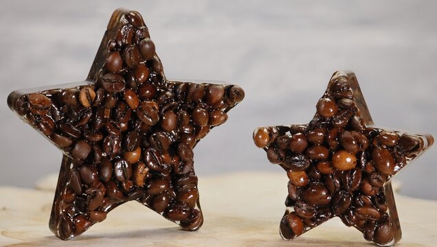 Two stars of different sizes formed from roasted coffee beans on a light background. Creative food concept representing quality, rating, and customer satisfaction, ideal for coffee branding, caf&eacute;s