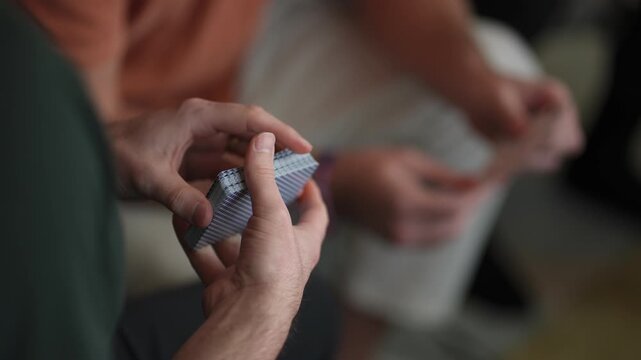 CloseUp Hands Fanning Playing Cards Showing Skillful Flourish And Precise Finger Control, Textured Blue Card Backs, Blurred Seated