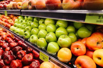 Fresh apples on supermarket shelves. Green red and yellow fruits in grocery store display. Healthy food choice concept. Retail produce section closeup. Abundance of organic fruit