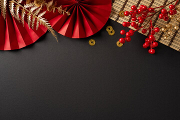 A festive setup for Chinese New Year featuring red fans, berries, and gold accents against a dark background, evoking celebration and warm greetings for the holiday season