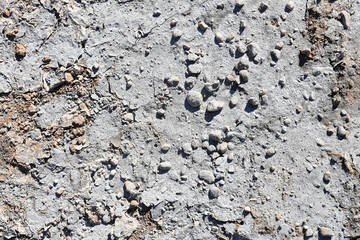 Rough concrete ground with small stones and gravel. Weathered gray surface texture detail. Urban pavement background from above. Construction material closeup. Abstract rough surface pattern