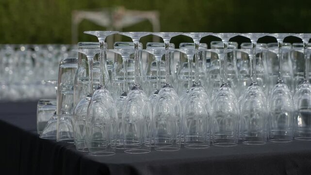 Rows Of Glassware Lined On Long Table, Inverted Crystal Stemware Polished And Arranged In Precise Rows, Soft Outdoor Light Creating
