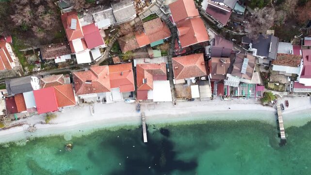 Aerial View of Trpejca Village on the Shores of Lake Ohrid, North Macedonia: Houses with Red Tile Roofs and Piers on the Coastline