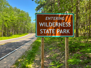 Entering Wilderness State Park Sign Post on the Side of the Road. Wilderness State Park is a public recreation area bordering Lake Michigan, in Emmet County in Northern Michigan.