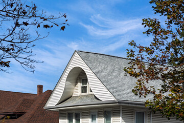 classic family home roofline with recessed attic window under a bright blue sky in Boston, Massachusetts, USA
