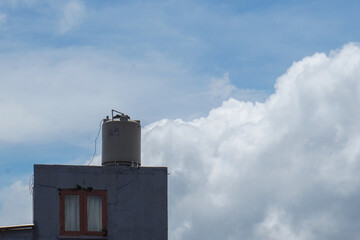 A gray water reservoir is kept on the roof of the building. The clear sky is the main background,...