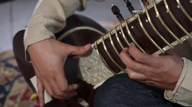 CloseUp Sitar Hands Plucking Strings In Intimate Home Studio, Session Musician Practicing Raga Phrases On Ornate Instrument, Warm Natural