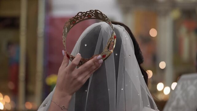 Bride Receiving Ornate Crown Over Veil In Church Crowning Ritual, Hand Placing Crown Glints With Jewels, Soft Candlelight And Ceremonial