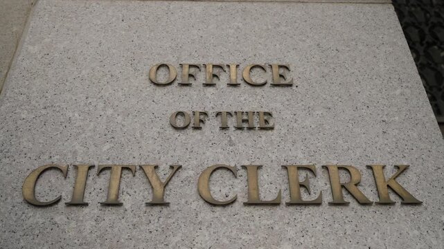 Bronze City Clerk Letters On Stone Plaque, CloseUp Angled Composition Showing Embossed Lettering And Textured Concrete, Official Municipal