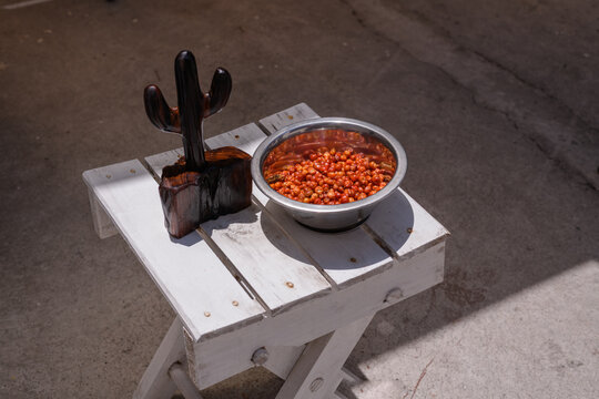 Bowl of chiltepin peppers next to a wooden cactus chiltepinero