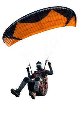 athletic male pilot in a high-tech suit and black helmet, suspended under a vast orange and black paraglider wing; sharp studio lighting against transparent background. concept of extreme