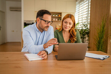 Obraz premium Couple working on laptop together at home office
