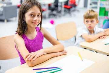 Smiling schoolgirl sitting at a desk in a modern STEM classroom, looking confident and engaged. Concept of future education, digital learning, creativity, and smart kids. Ideal for back-to-school