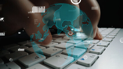 A close-up of hands typing on a modern keyboard is enhanced with a transparent digital globe overlay and data visualizations, representing technology and global connectivity. Xenic