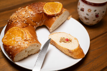 Sliced traditional Spanish Roscon de Reyes cake, the cut piece reveals the hidden prize, a bear figurine holding a heart, , traditional Spanish ring cake for Epiphany celebration