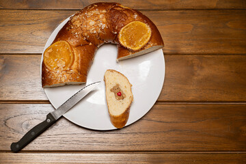 traditional Spanish Roscon de Reyes cake, the cut piece reveals the hidden prize, a small bear figurine holding a heart, , traditional Spanish ring cake for Epiphany celebration