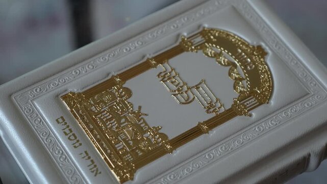 White Book With Gold Embossing, Ornate Arch Motif Framed By Decorative Border, Soft Natural Light Highlights Textured Cover And Fine