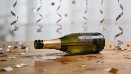 Celebratory champagne bottle lying on a wooden table with confetti  