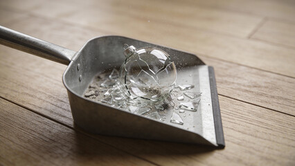 Broken glass shards in metal pan on wooden floor  