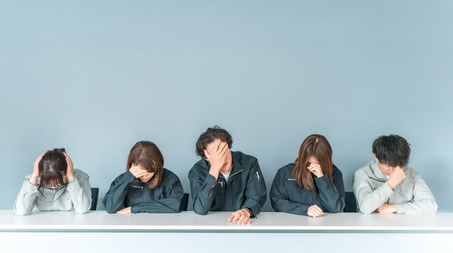 A businessman and woman in work clothes holding their heads