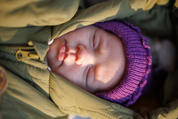 Portrait of a sleeping newborn baby outdoors in winter