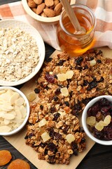 Tasty granola bars with dried fruits and nuts on black wooden table, flat lay