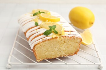 Delicious lemon cake with glaze, fresh fruit slices and mint on light table, closeup